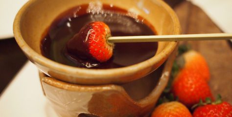 ANAインターコンチネンタルホテル東京のアフタヌーンティーメニュー、チョコフォンデュの写真。溶けたチョコレートに、ピックで差した苺を絡めているところ